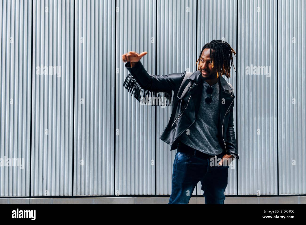 Young man gesturing in front of wall Stock Photo