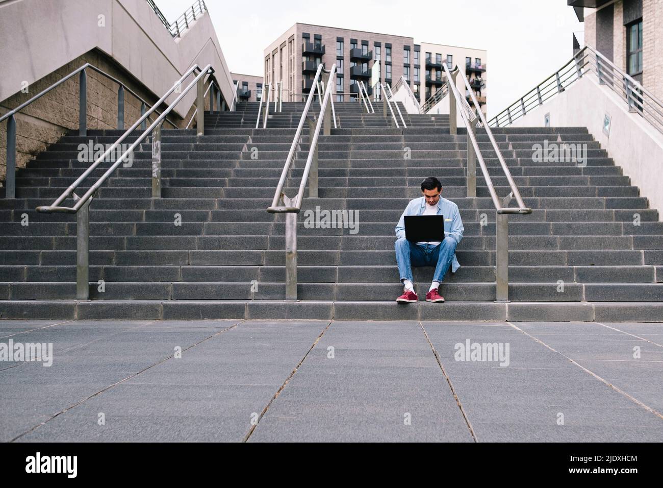 Man using laptop sitting on staircase Stock Photo