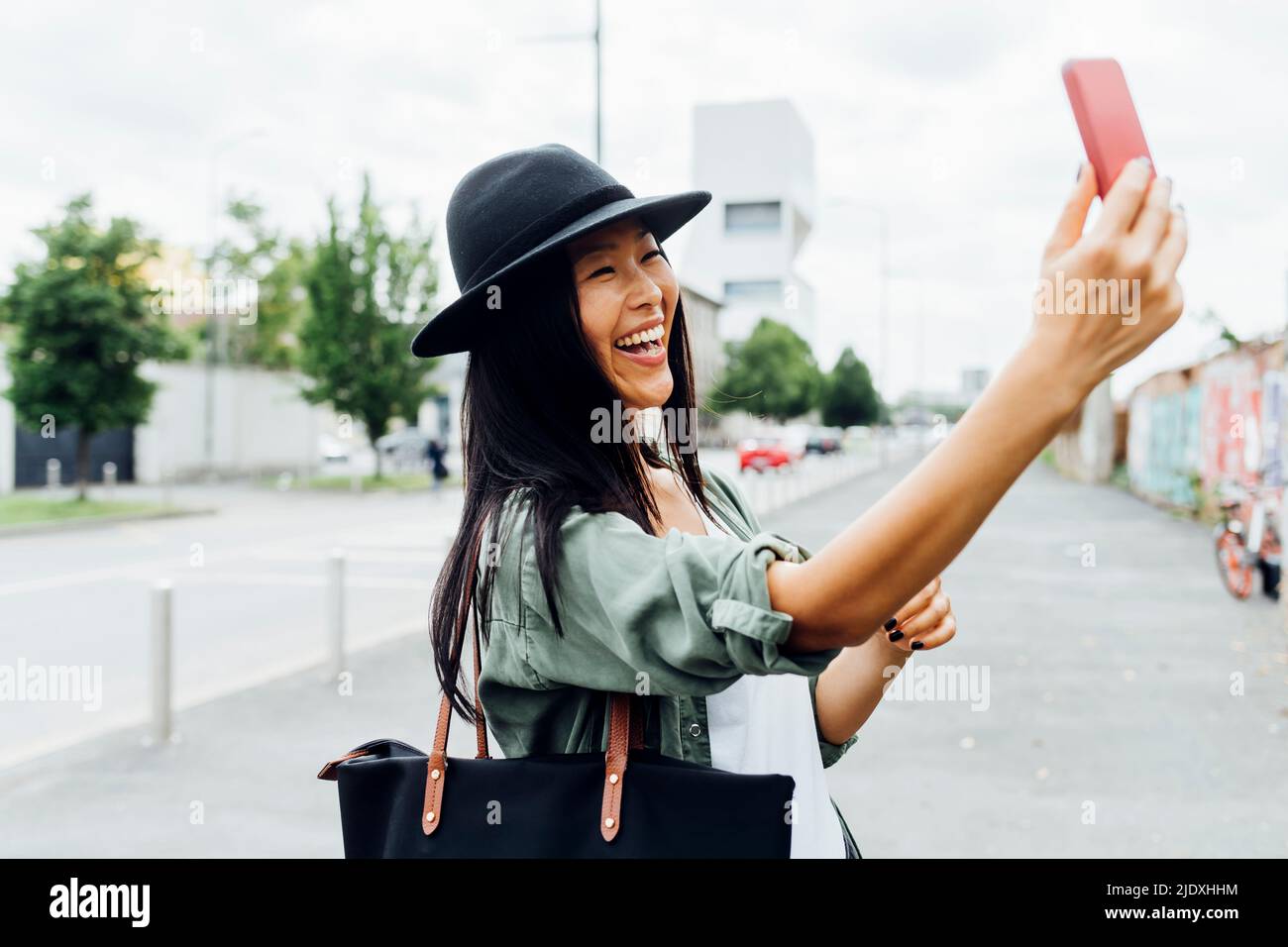 Cheerful young woman doing video call through mobile phone Stock Photo ...