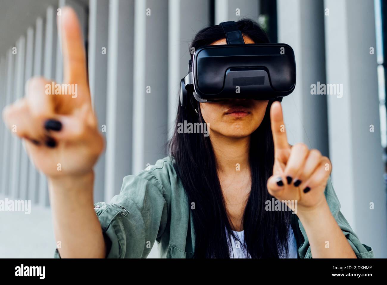 Young woman wearing VR simulator pointing Stock Photo