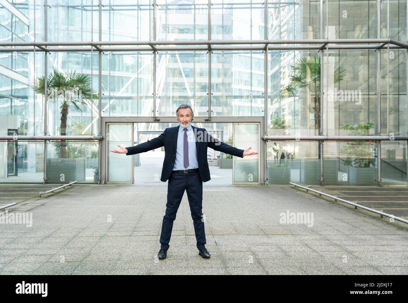Businessman with arms outstretched standing in front of modern glass