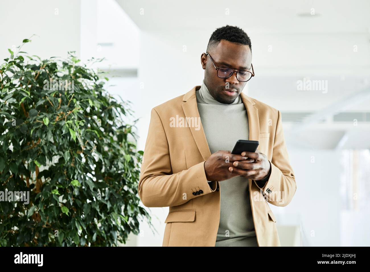 Young businessman text messaging through smart phone in office Stock Photo
