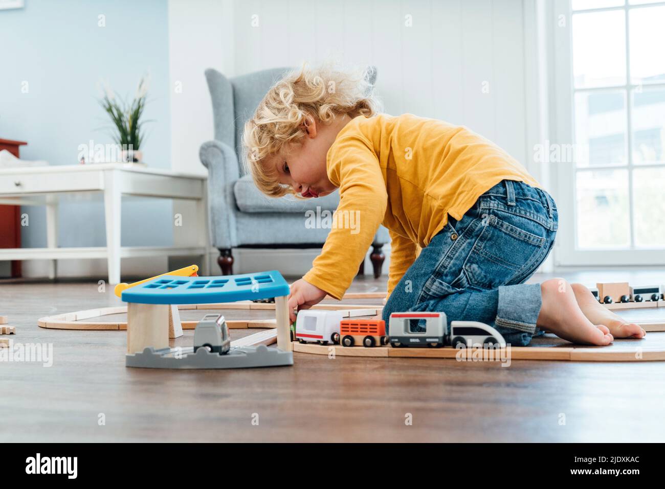 Blond boy playing with toy train set at home Stock Photo