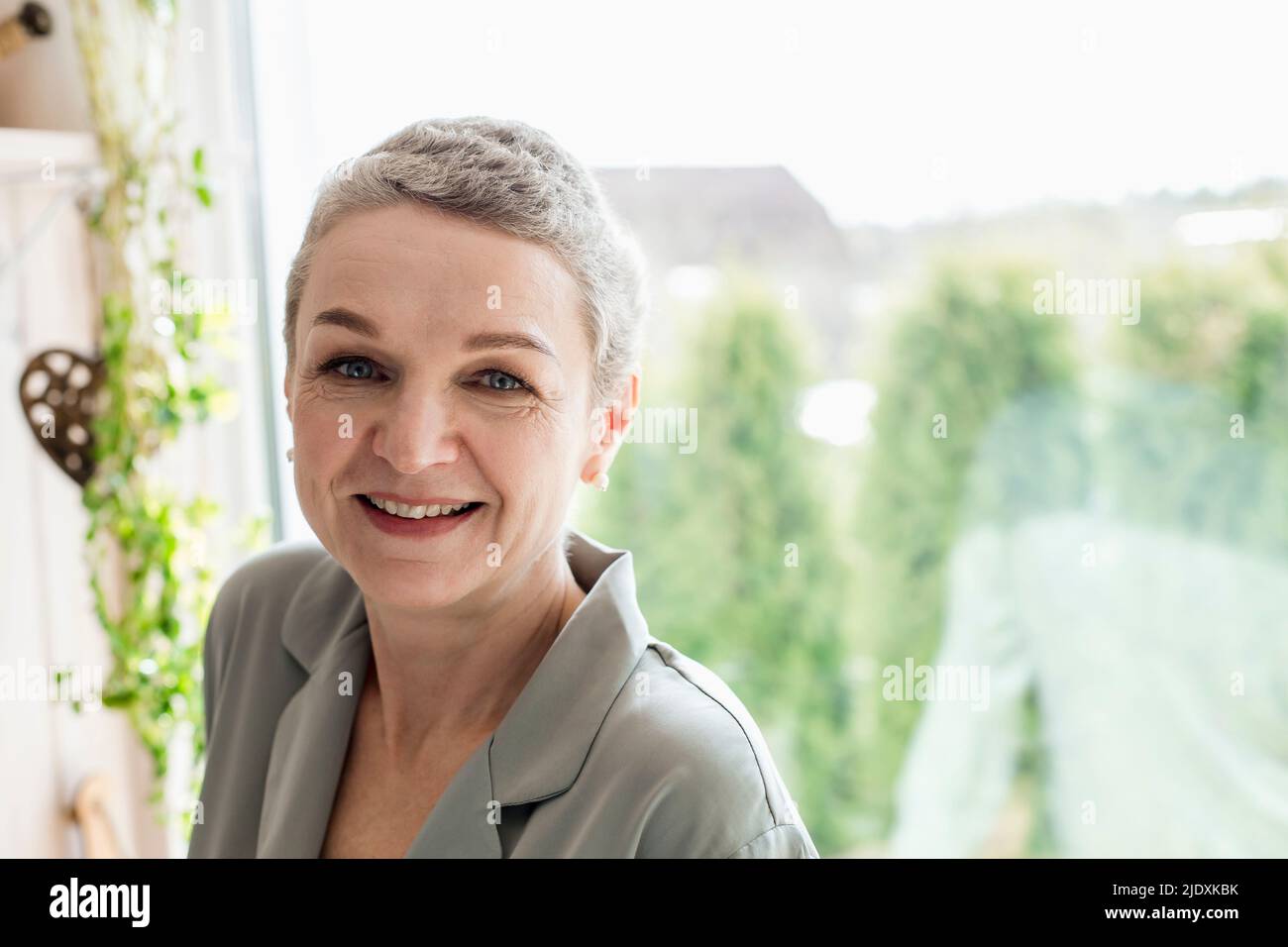 Portrait of mature woman with short grey hair at the window Stock Photo