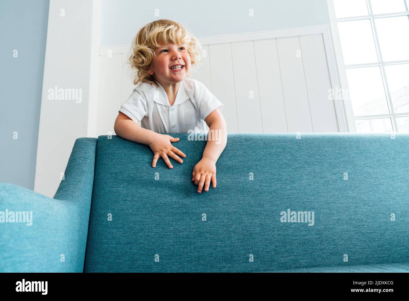 Cute boy climbing on sofa in living room at home Stock Photo Alamy