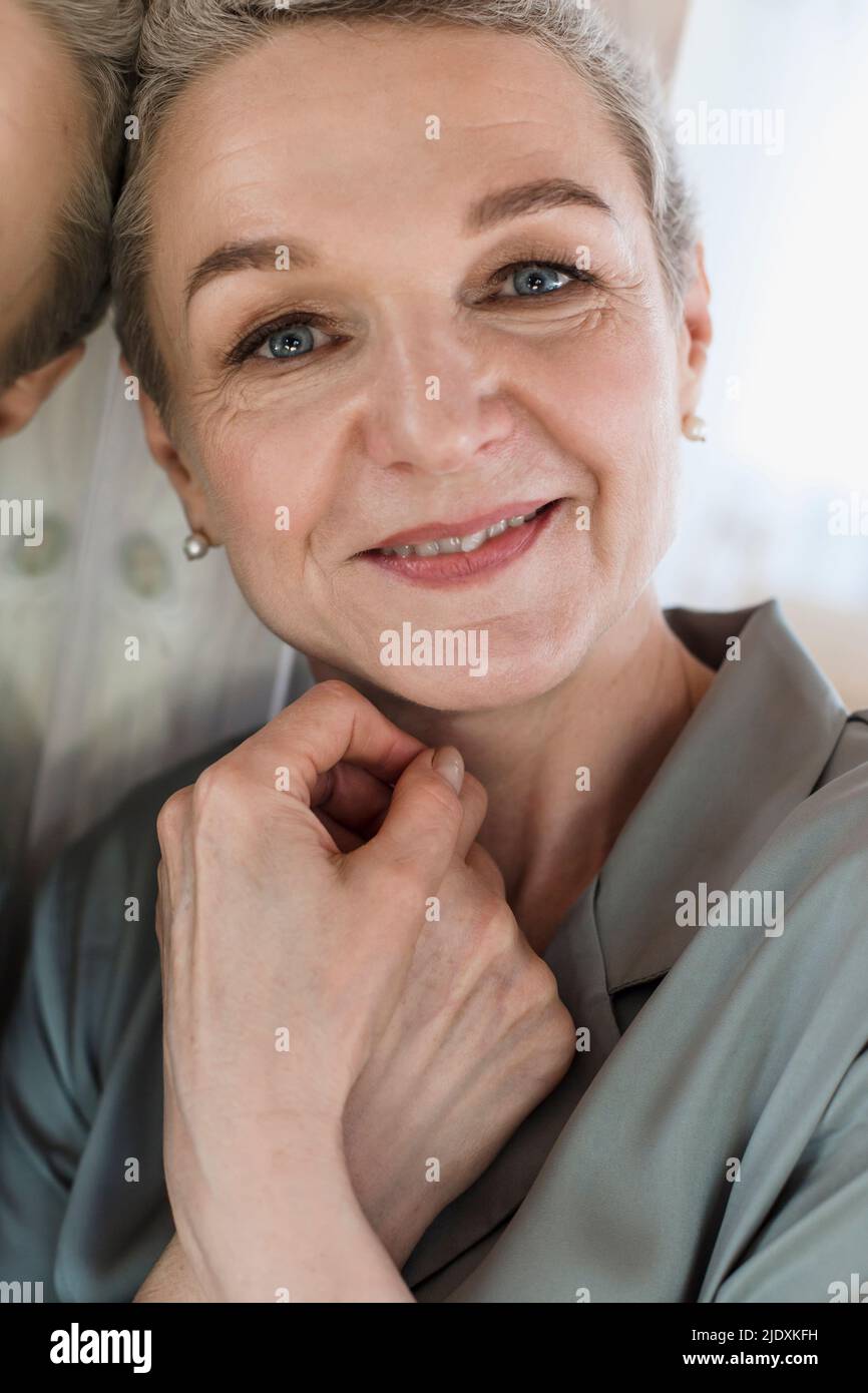 Portrait of mature woman with short grey hair leaning against mirror Stock Photo