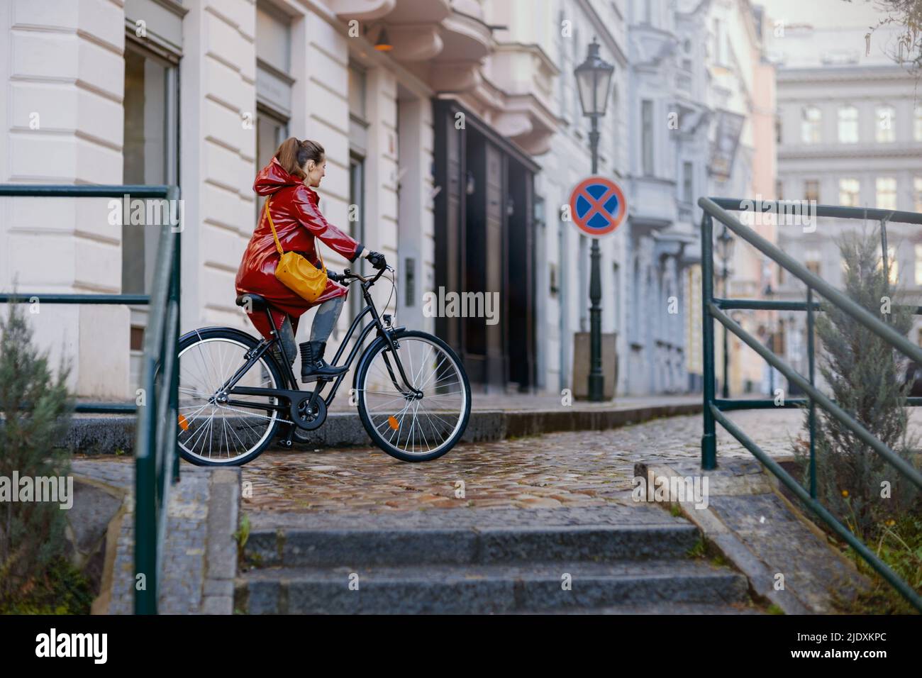 stylish middle aged woman in red rain coat outside on the city street ...