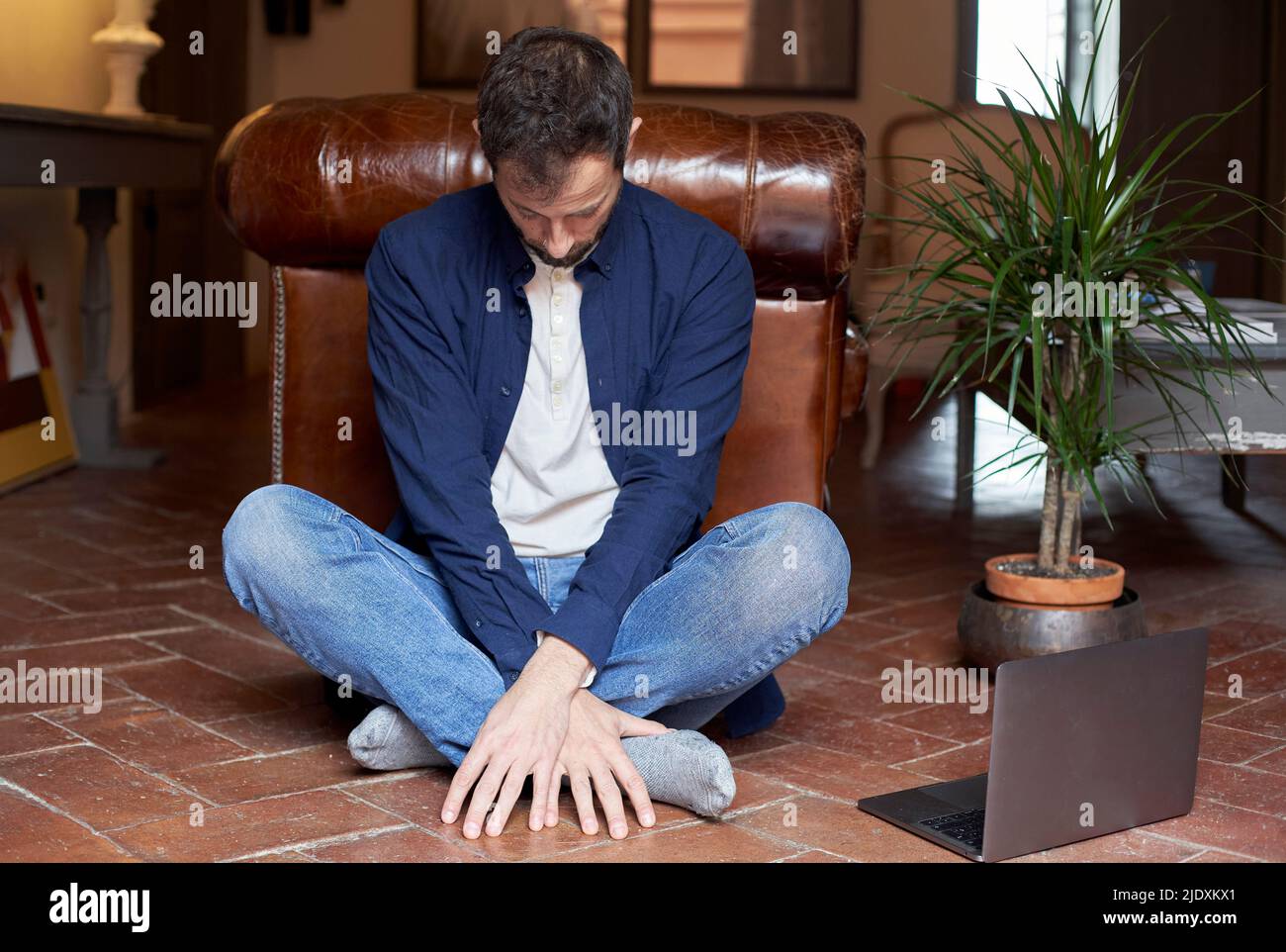 Man sitting cross-legged by laptop on floor at home Stock Photo - Alamy