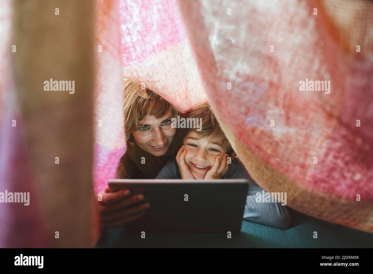 Happy mother and son using tablet PC under blanket Stock Photo