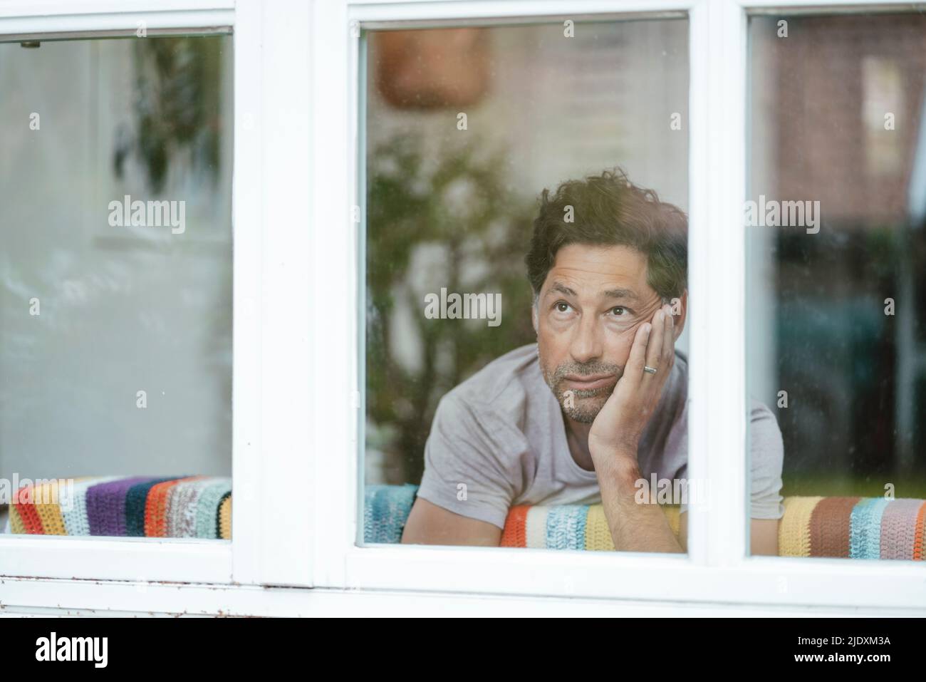 Thoughtful man looking through window Stock Photo