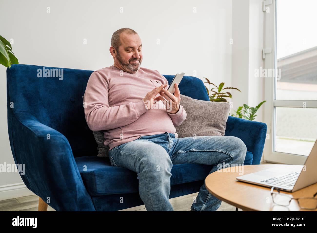 Smiling freelancer using smart phone at home Stock Photo