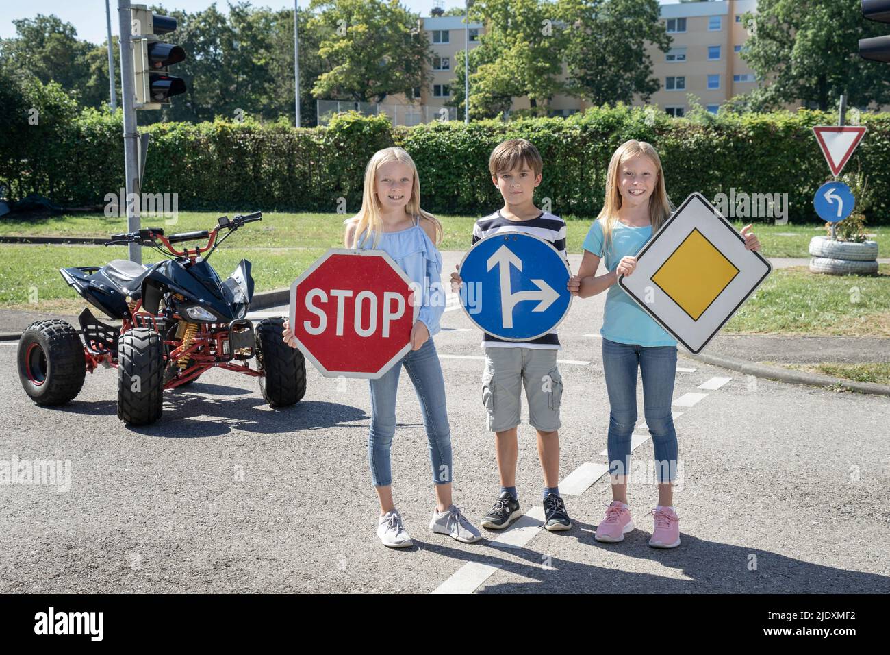 Smiling children holding road signs board on standing road Stock Photo