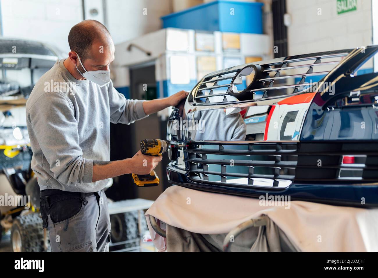 Auto mechanic repairing vehicle body part with electric screwdriver