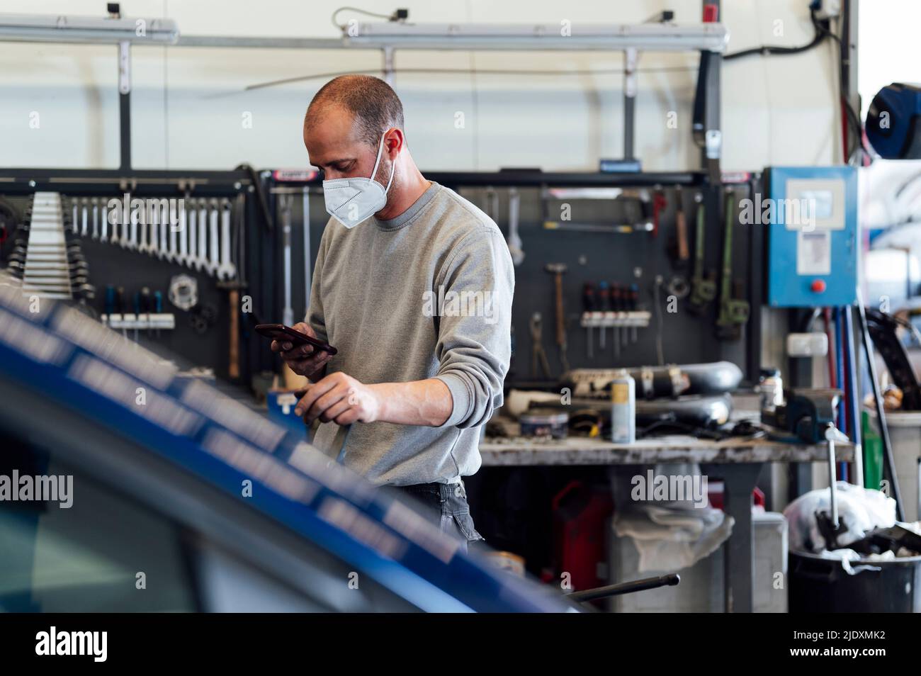 Mechanic using mobile phone in auto workshop Stock Photo