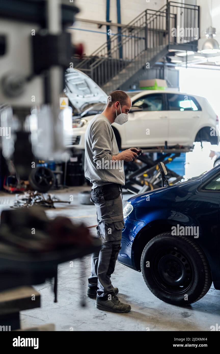 Happy Car Mechanic Busy Using Mobile Phone at Garage in Front of Repair Car  with Opened Hood - Concept of Using Stock Image - Image of engineer,  professional: 243464133