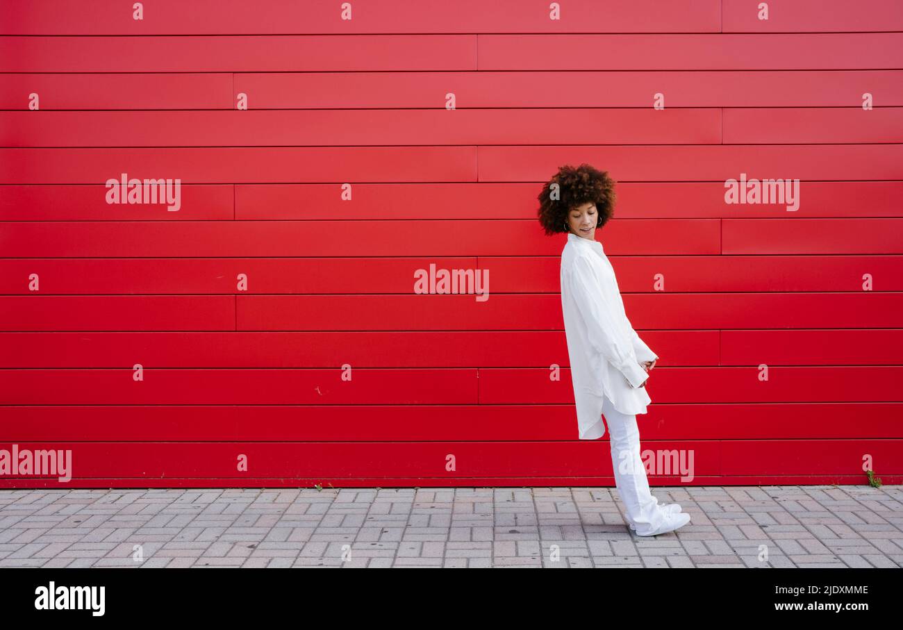 Young woman leaning backward by red wall Stock Photo