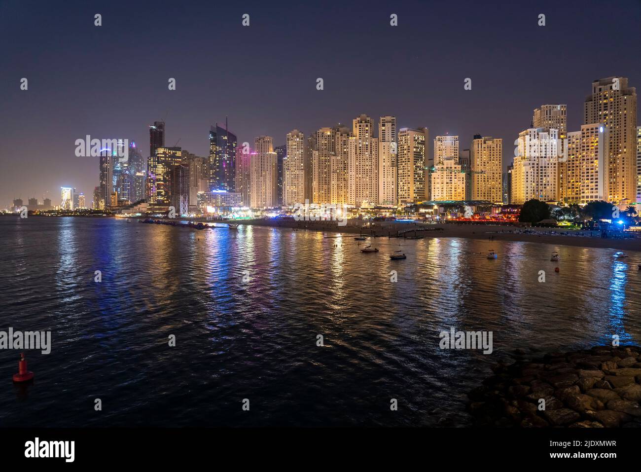 United Arab Emirates, Dubai, Skyline of illuminated coastal apartments at night Stock Photo