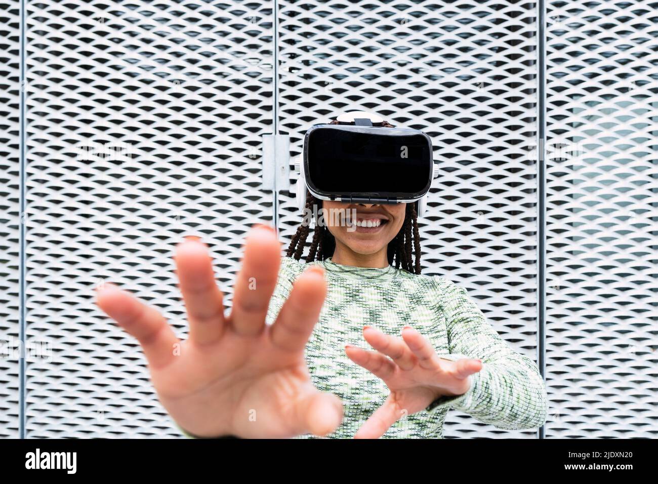 Smiling young woman wearing virtual reality simulator gesturing in ...
