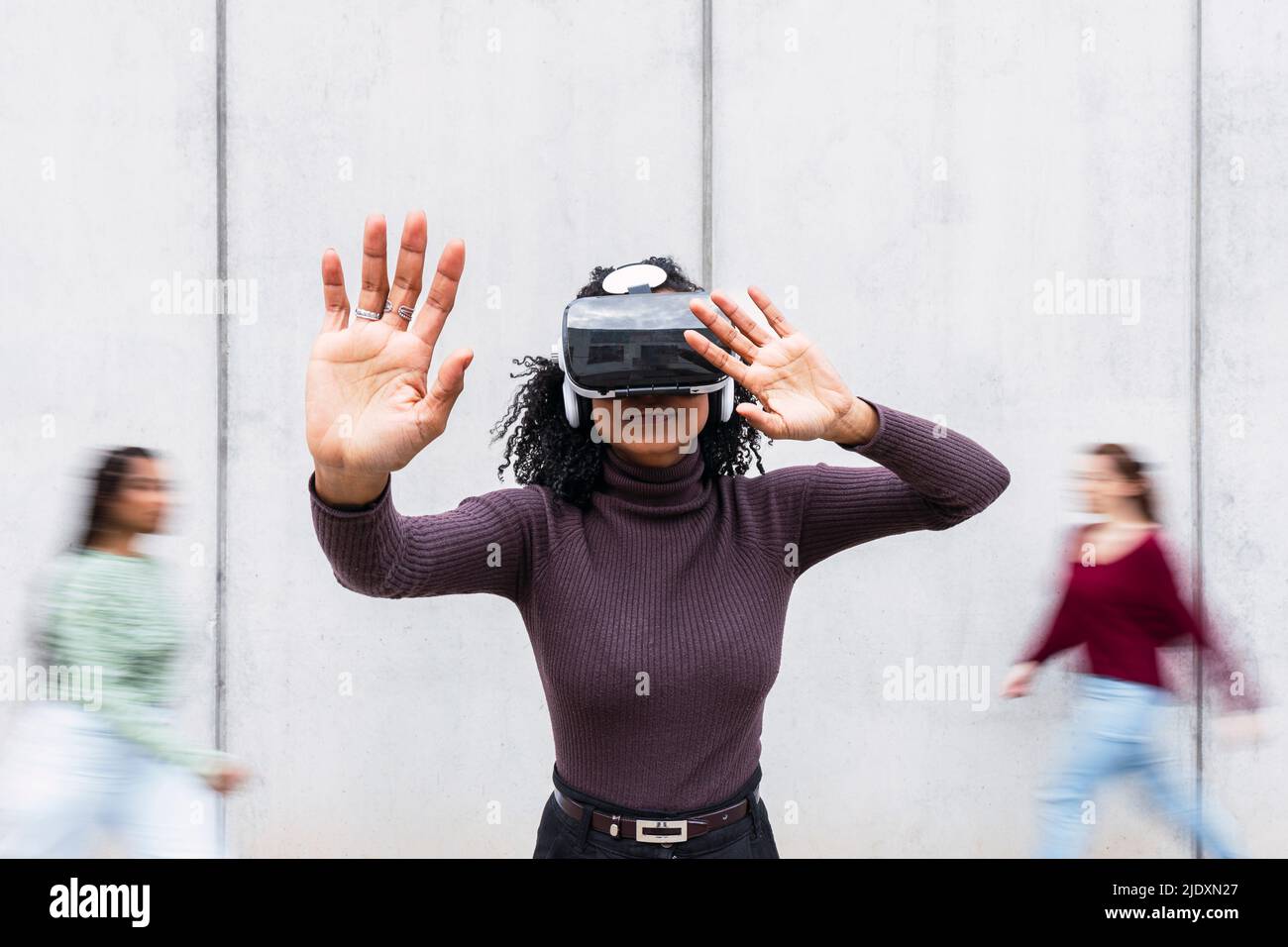 Smiling woman wearing virtual reality simulator gesturing in front of ...