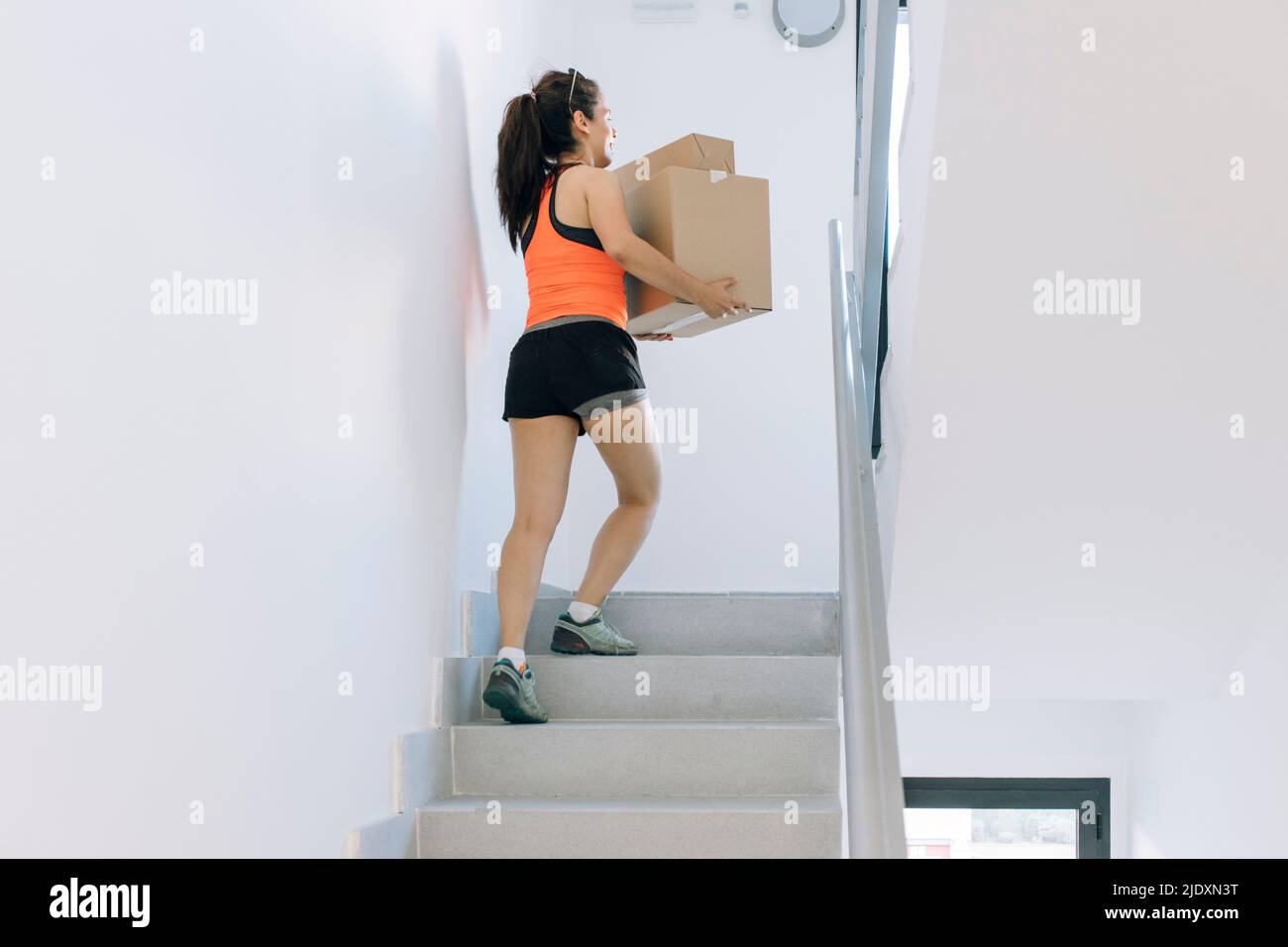 Woman carrying cardboard boxes moving up on steps Stock Photo Alamy