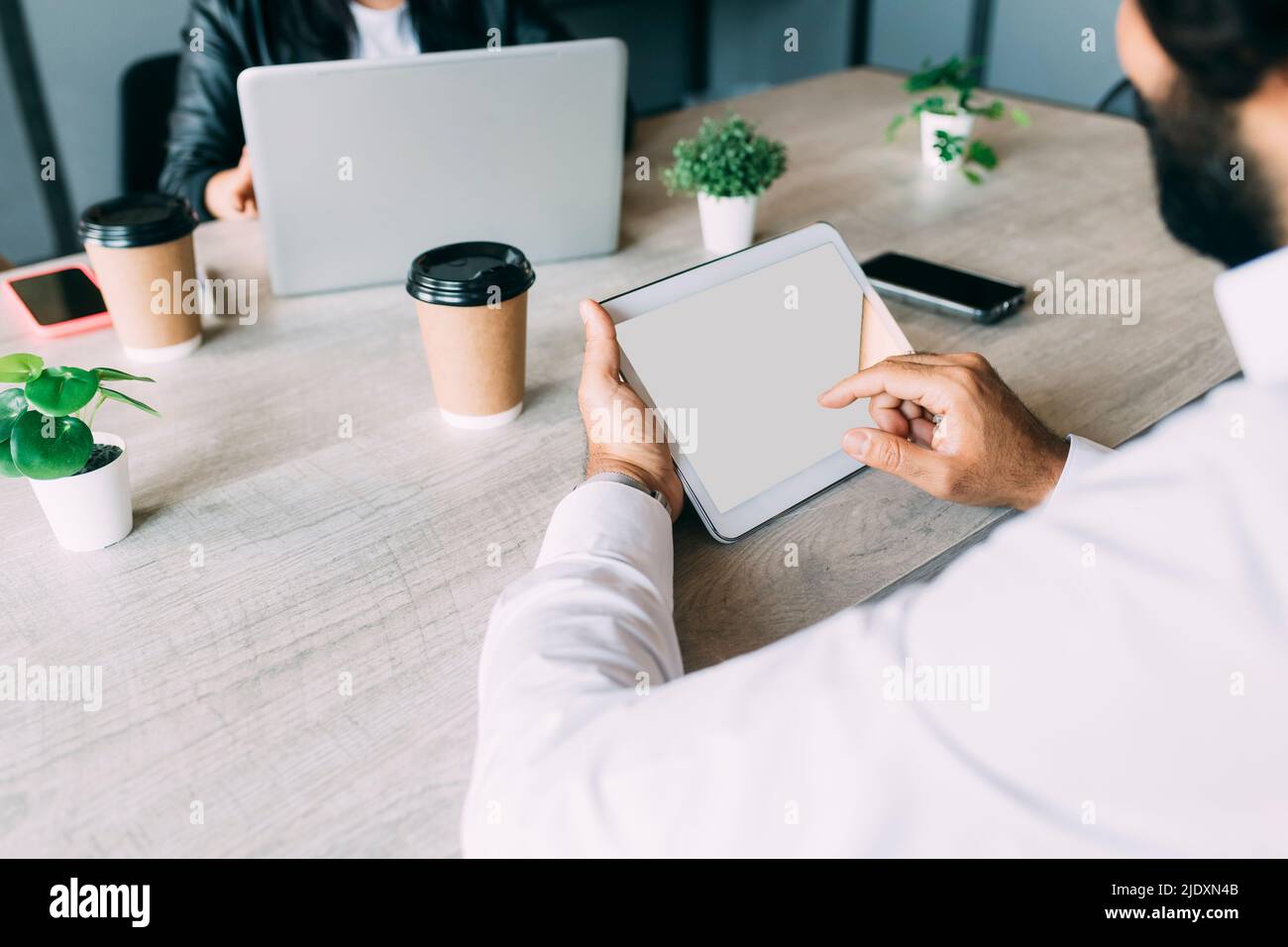 Businessman using tablet computer by colleague at work place Stock Photo