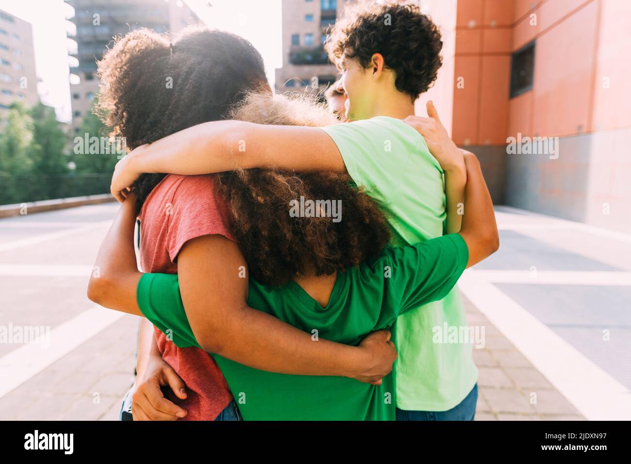 Young woman hugging boys on sunny day Stock Photo