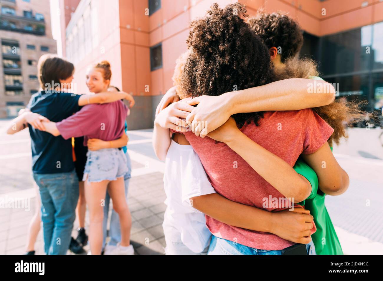 Friends huddling together on sunny day Stock Photo