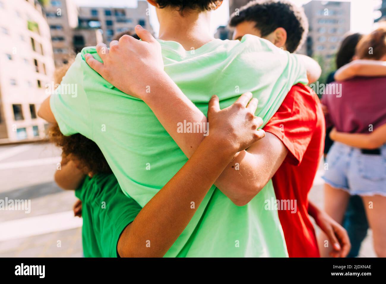 Multiracial friends hugging each other standing on footpath Stock Photo