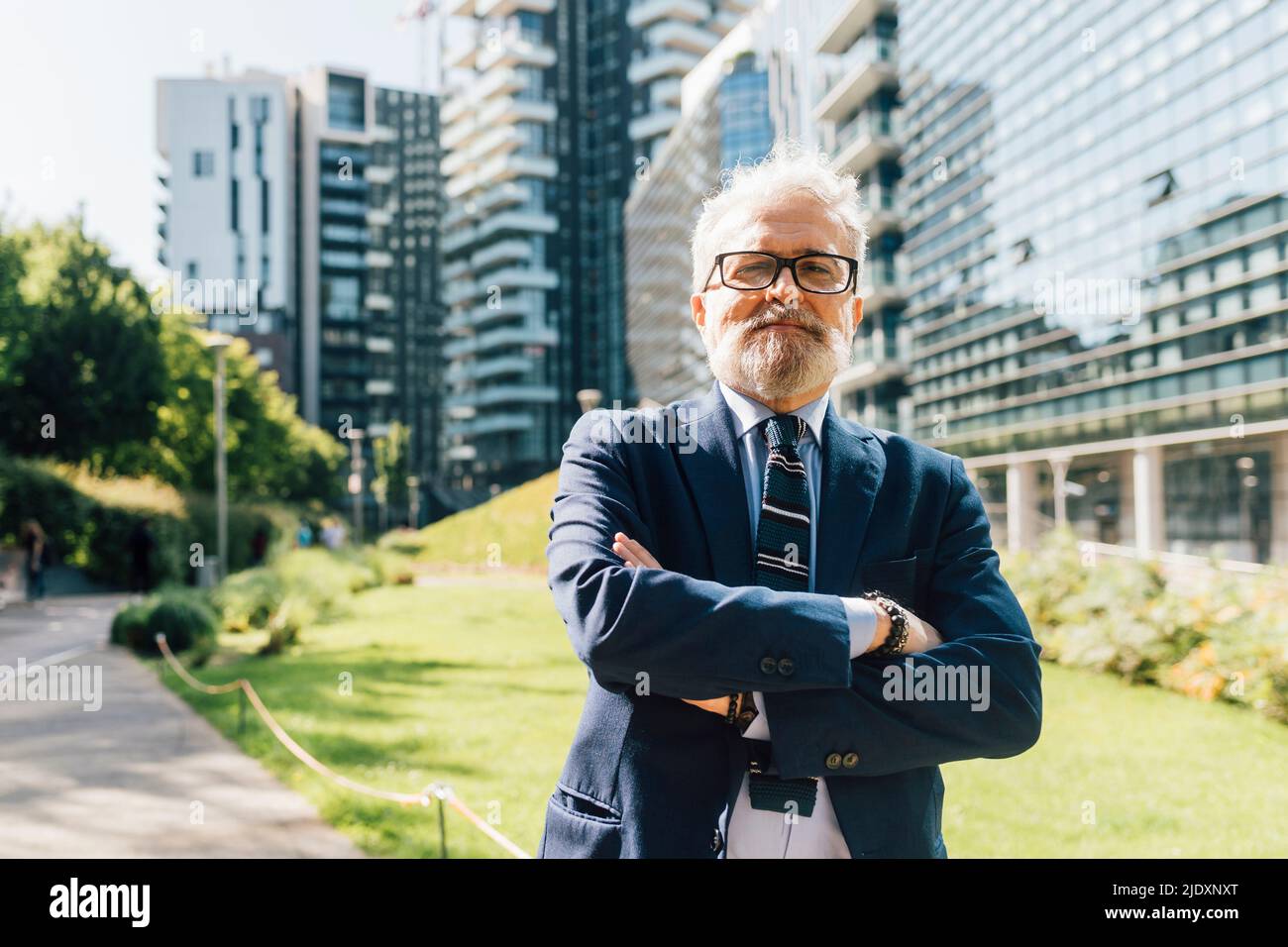 Senior businessman posing with arms crossed outside office building on ...
