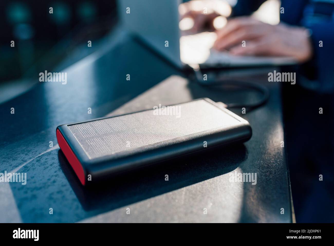 Solar battery charger connected to laptop being used by businessman Stock Photo