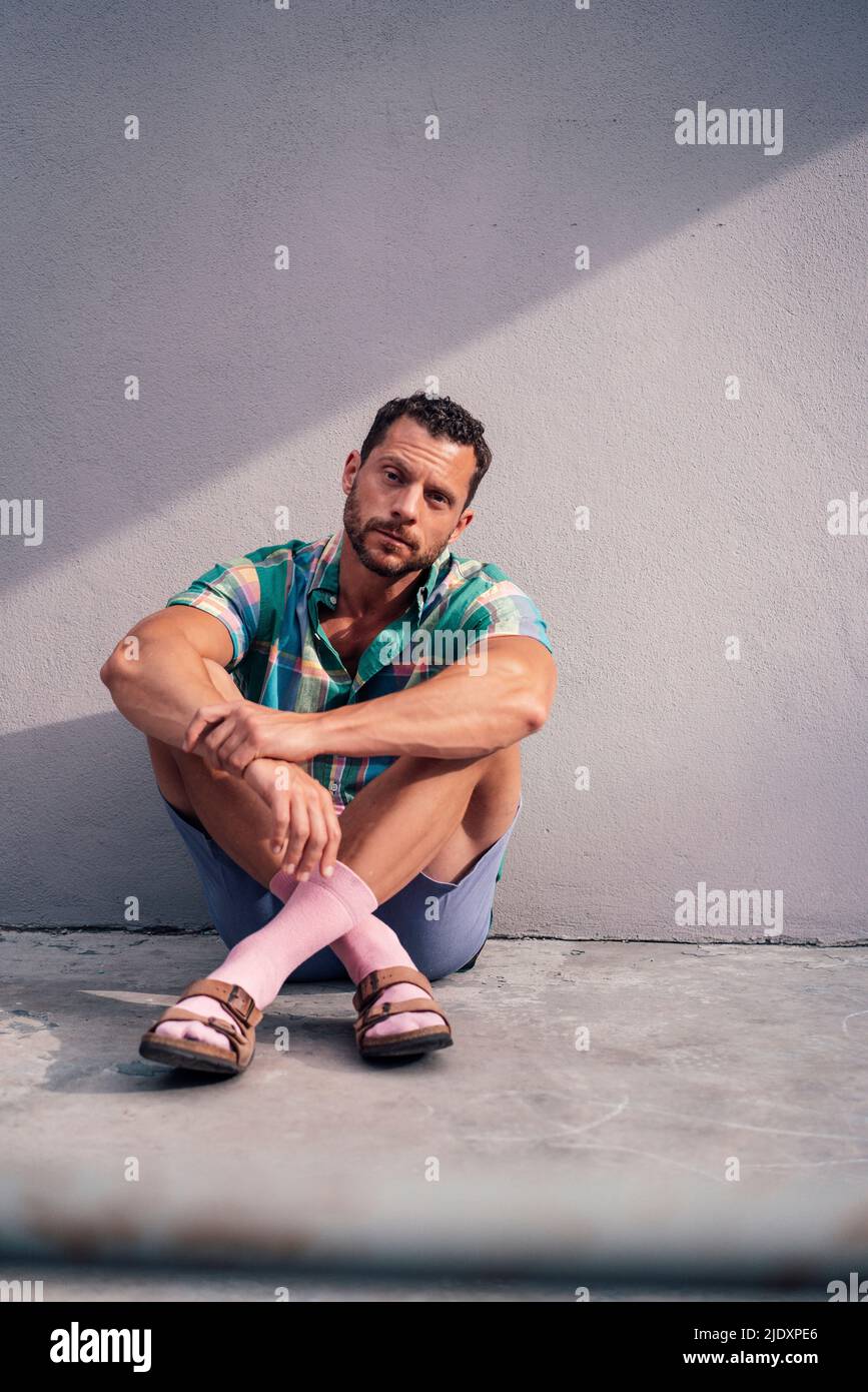 Man sitting cross-legged on floor near concrete wall Stock Photo - Alamy