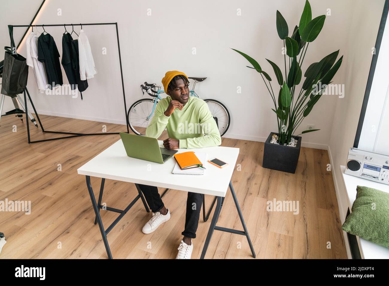 Young freelancer with hand on chin at home Stock Photo