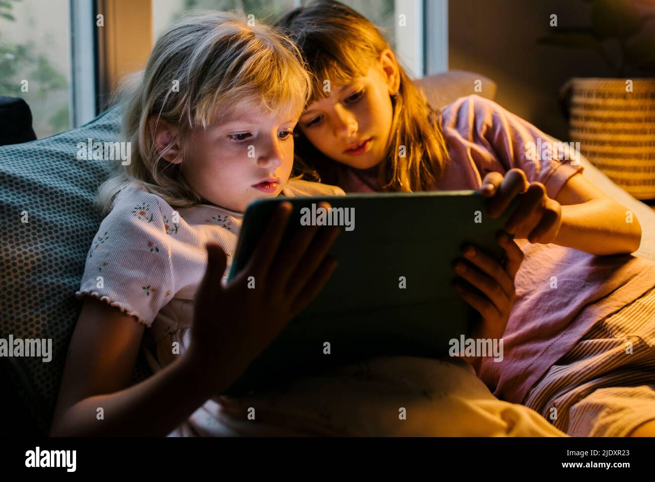 Sisters watching tablet PC at home Stock Photo