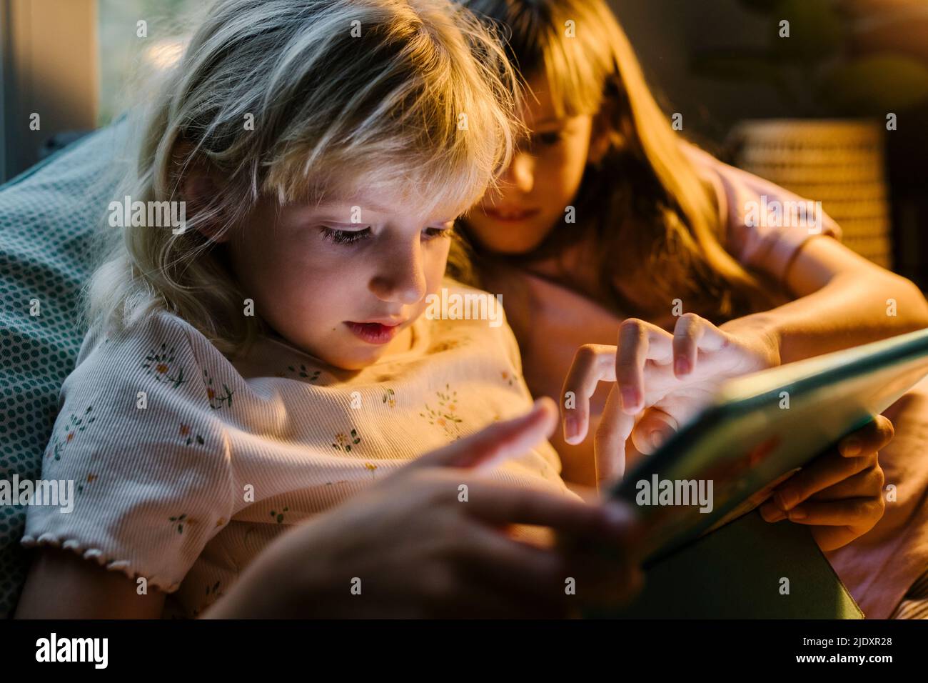 Sisters using tablet PC together at home Stock Photo
