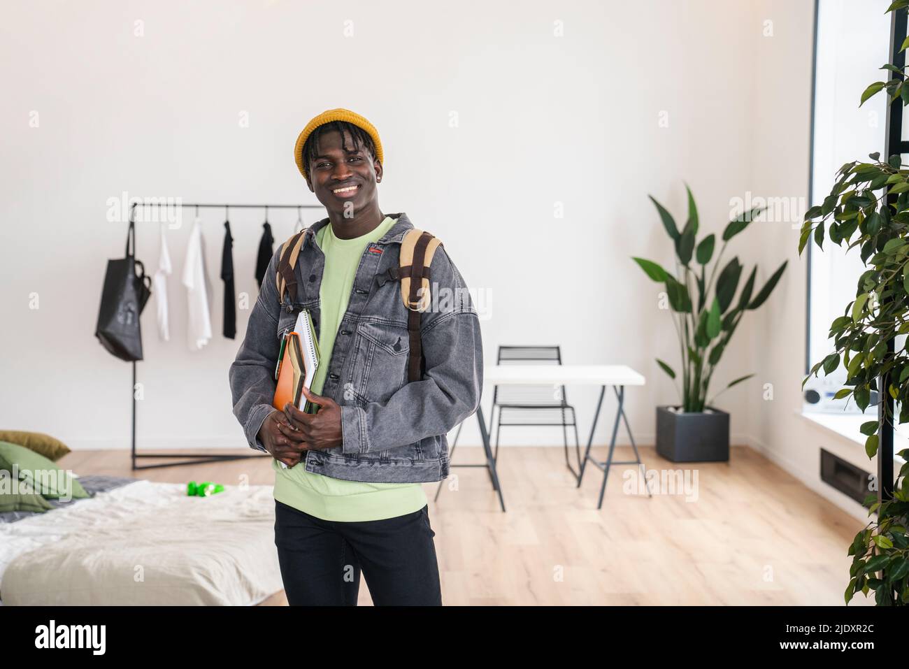 Smiling student with books in bedroom Stock Photo