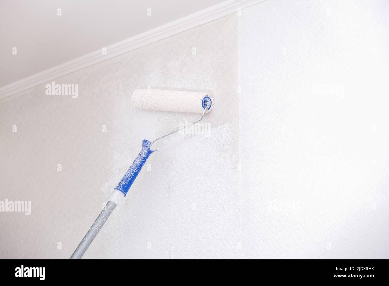 A man is painting vinyl wallpaper with a velour roller for painting