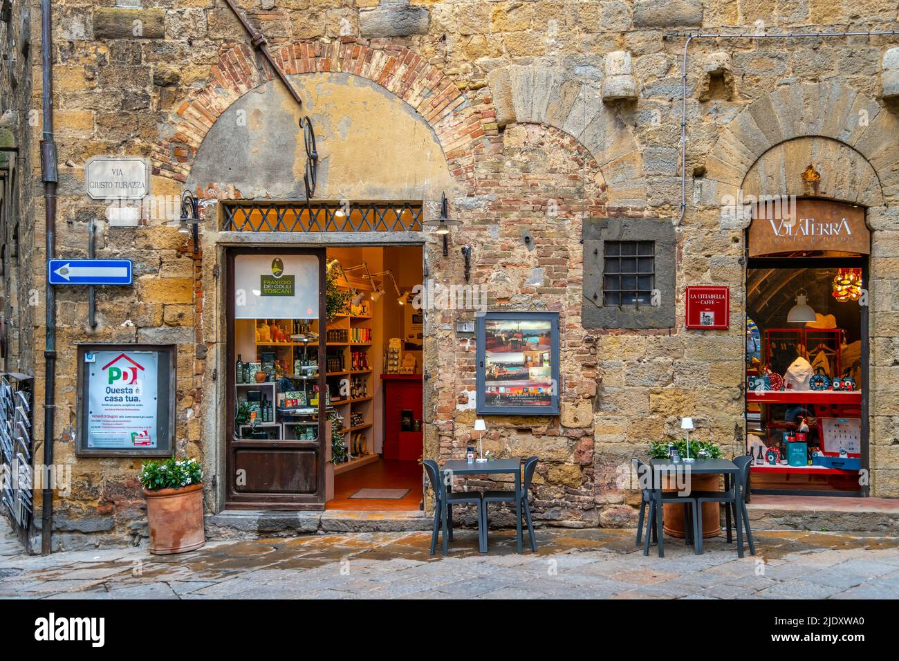 A picturesque cafe with tables on the sidewalk in front in the medieval center of the historic hill town of Volterra, Italy, in the Tuscan region. Stock Photo