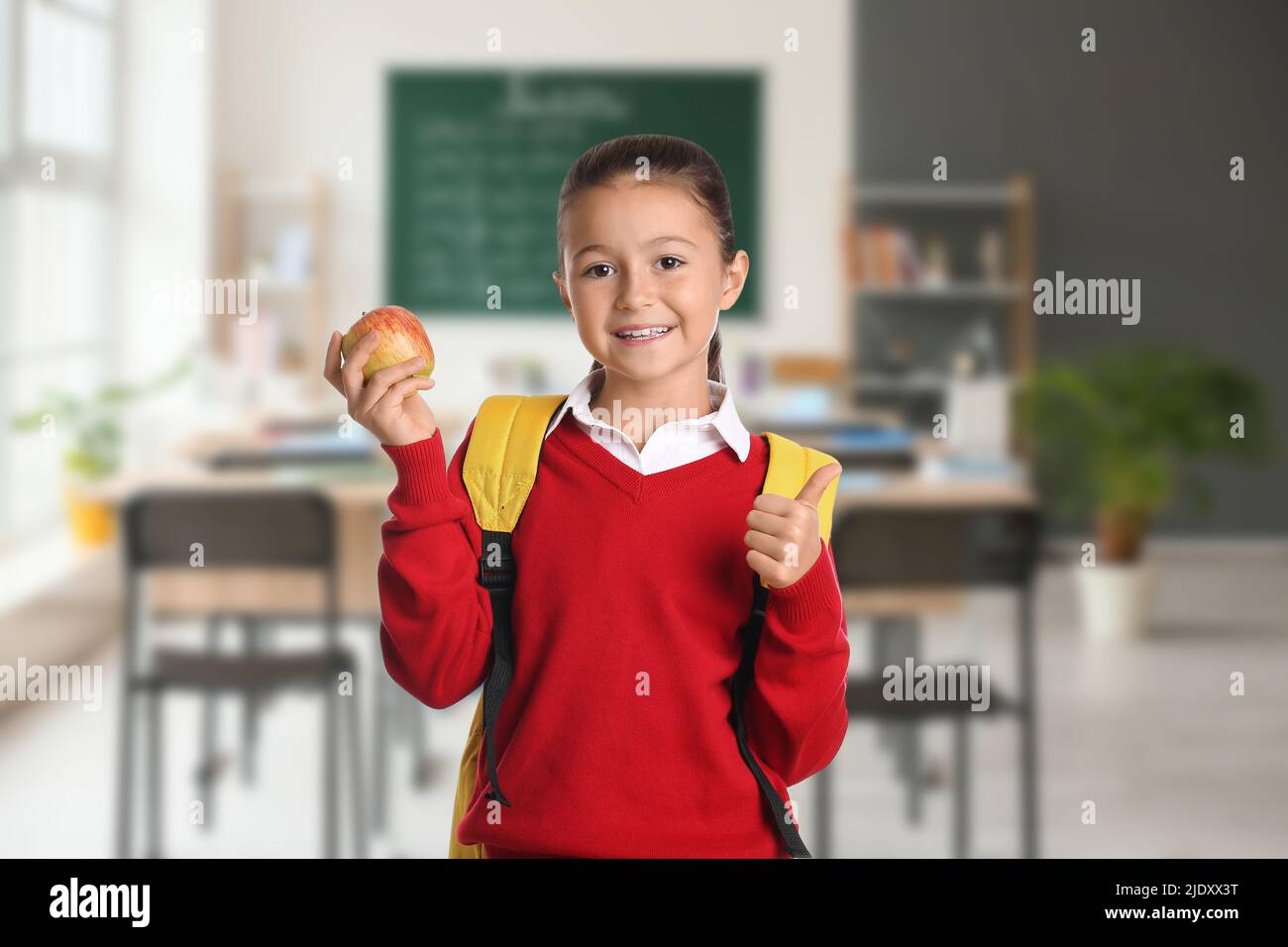 Little schoolgirl with apple in classroom Stock Photo - Alamy