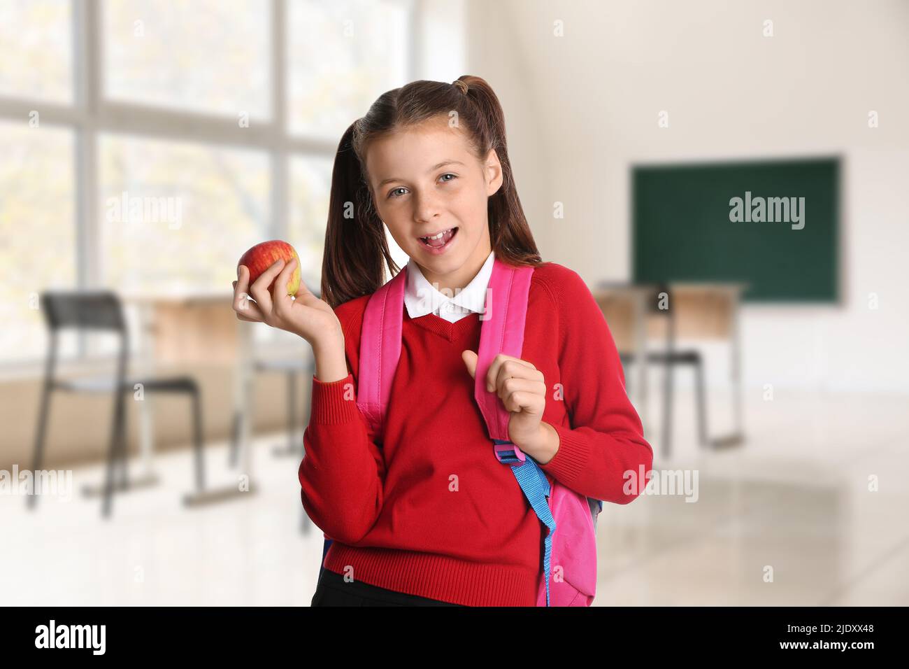 Little schoolgirl with apple in classroom Stock Photo - Alamy