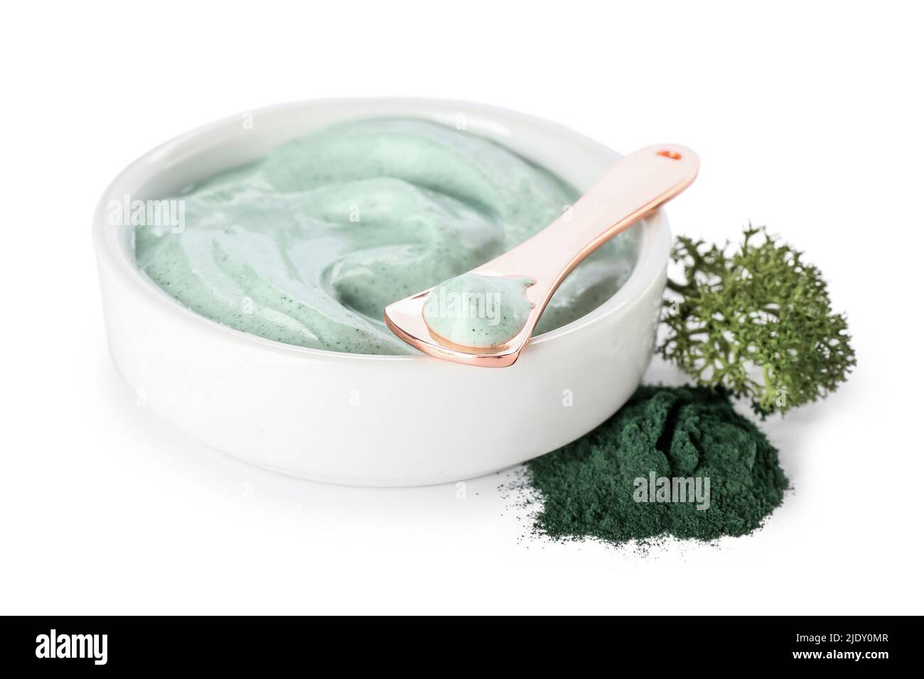 Bowl of spirulina facial mask, spatula and powder on white background