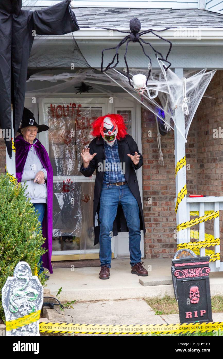 An costumed elderly couple, as a scary clown and a witch, await Trick