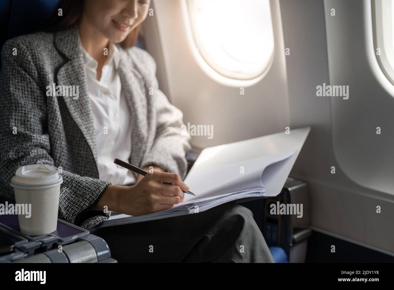 Close up hand of asian female entrepreneur working on paperwork finance report sitting near window in an airplane Stock Photo