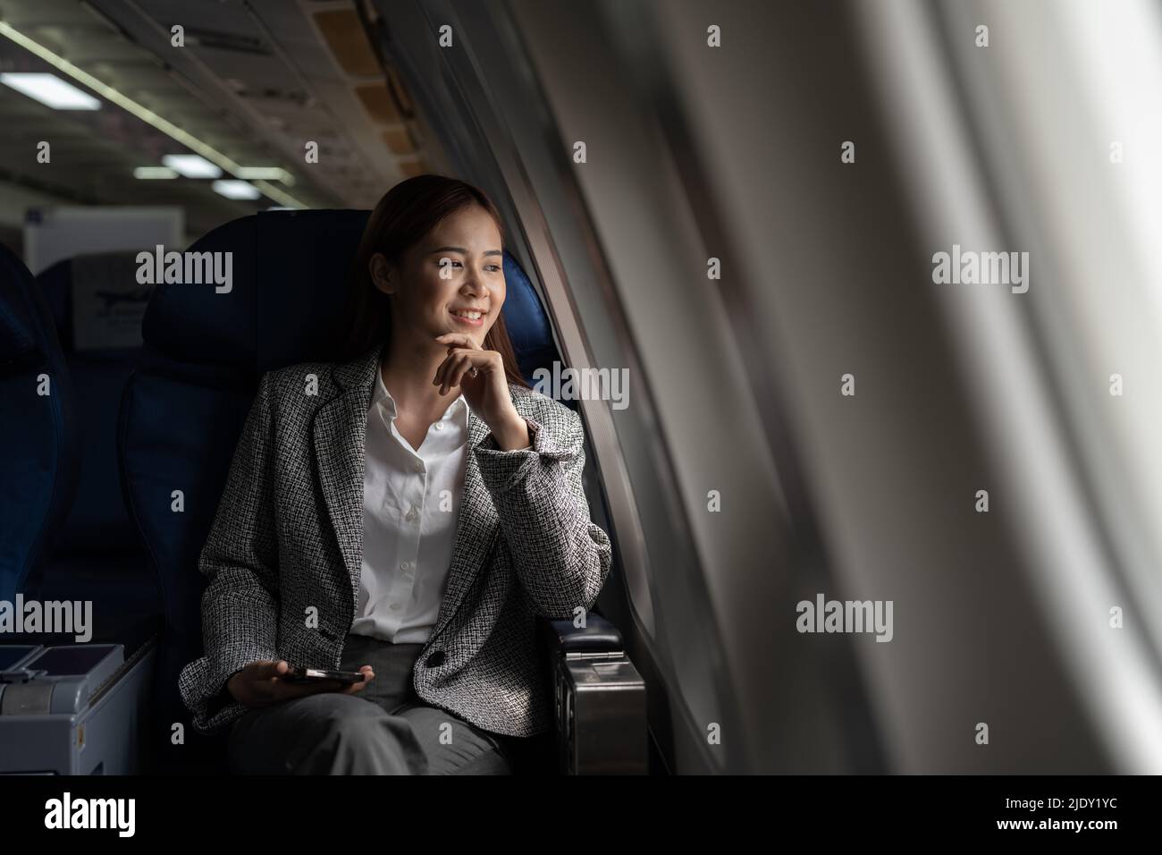 Young asian woman looking at the window in air plane, business travel and transport concept Stock Photo