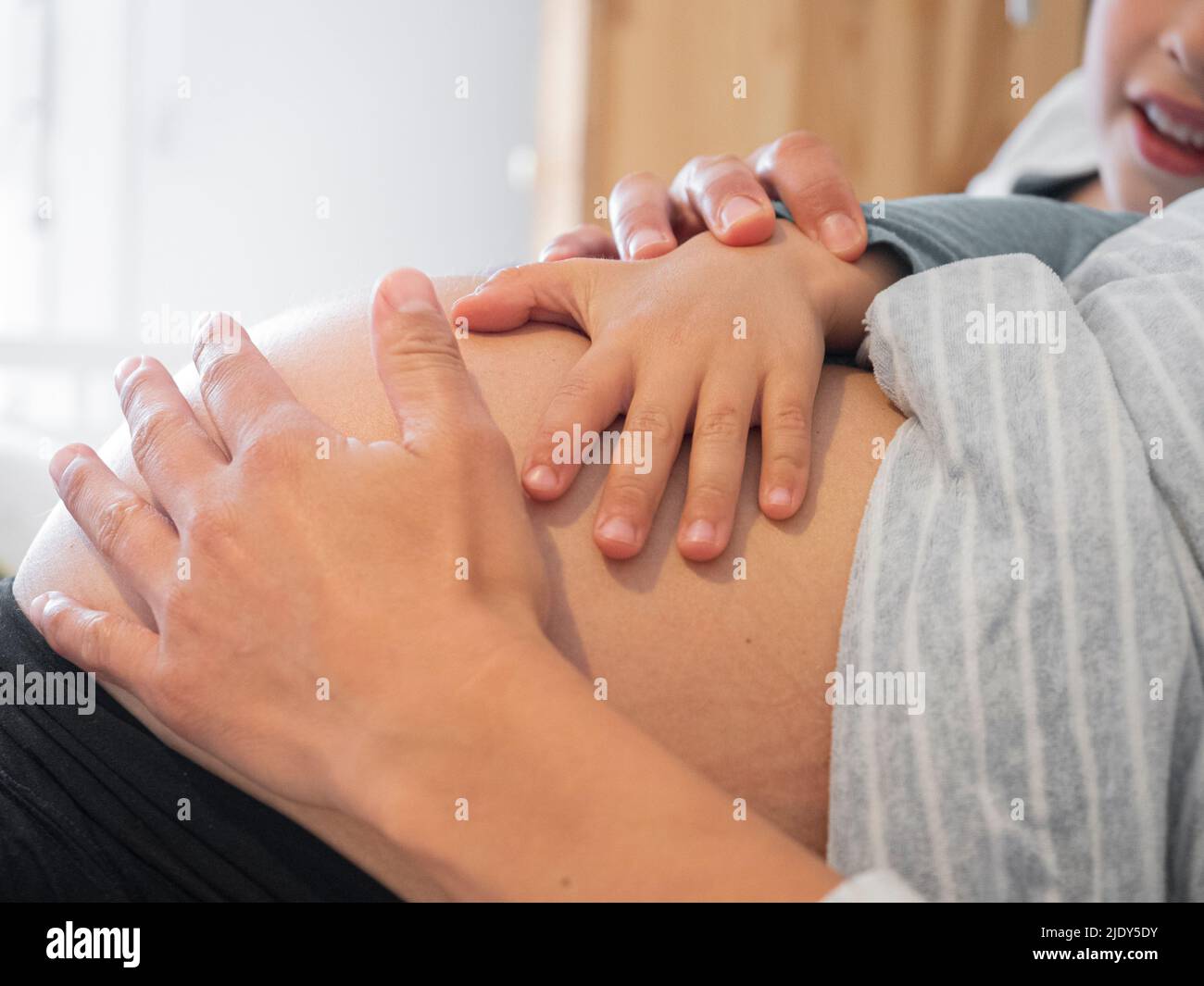 Child touching his pregnant mother's tummy Stock Photo