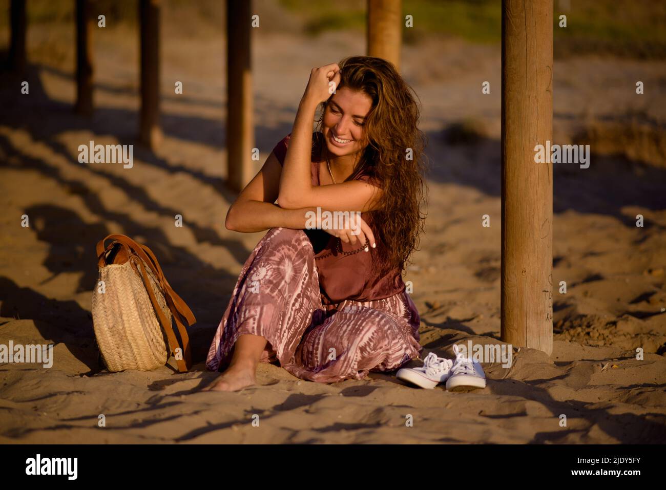 Caucasian young woman happy and sitting on the beach sand Stock Photo