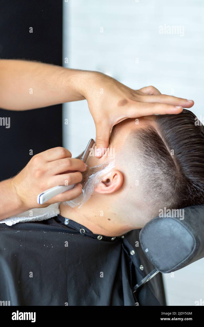 professional barber shaving a client with a razor Stock Photo