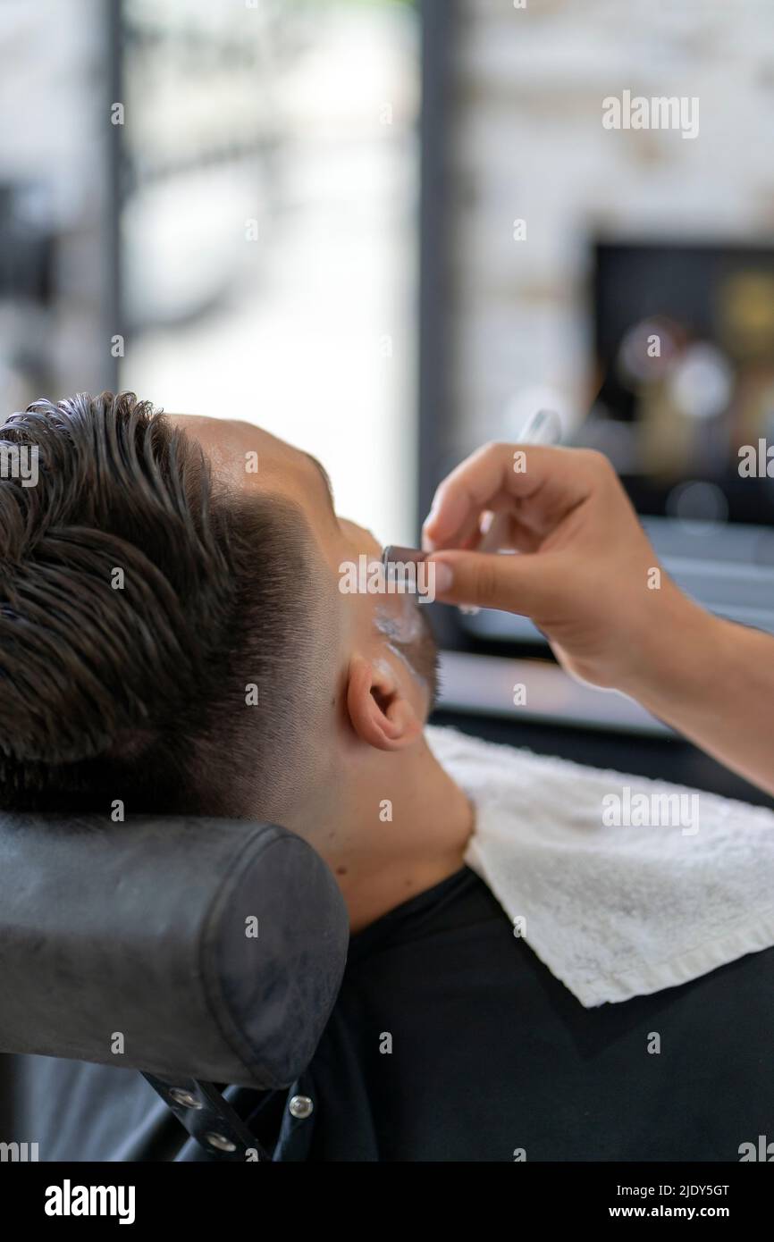 barber shaving a client with a razor Stock Photo
