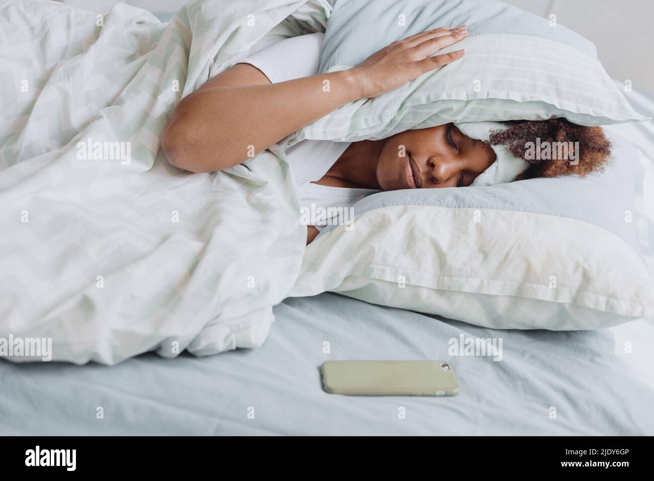 Woman sleeping in bed with a pillow on your head. Stock Photo