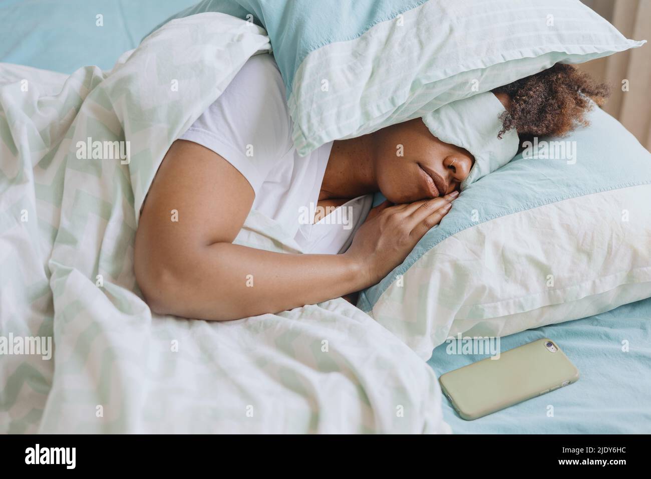 Curly  woman sleeping with sleep mask on her face. Stock Photo