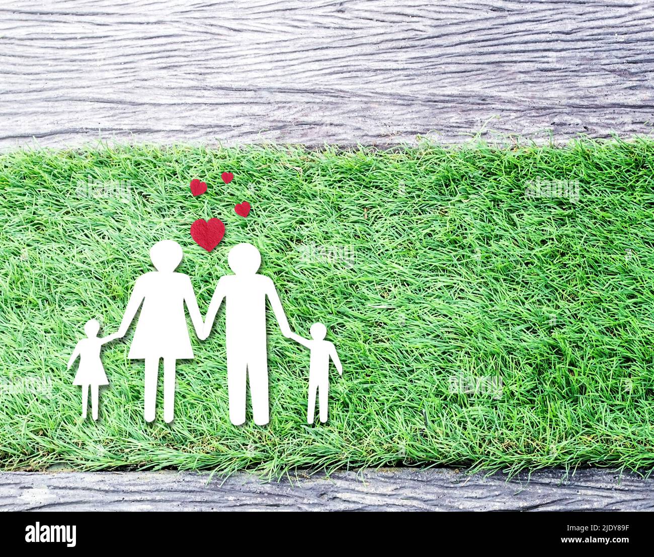 Top view with paper cut of family on grass with red hearts. Copy space ...